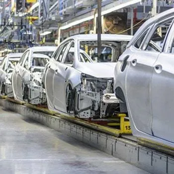 a row of white cars on a conveyor belt