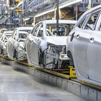 a row of white cars on a conveyor belt